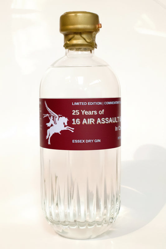 A clear glass bottle of Essex Dry Gin with a gold cap and a dark red label featuring a white winged horse graphic and text reading '25 Years of 16 Air Assault' and 'Essex Dry Gin'.
