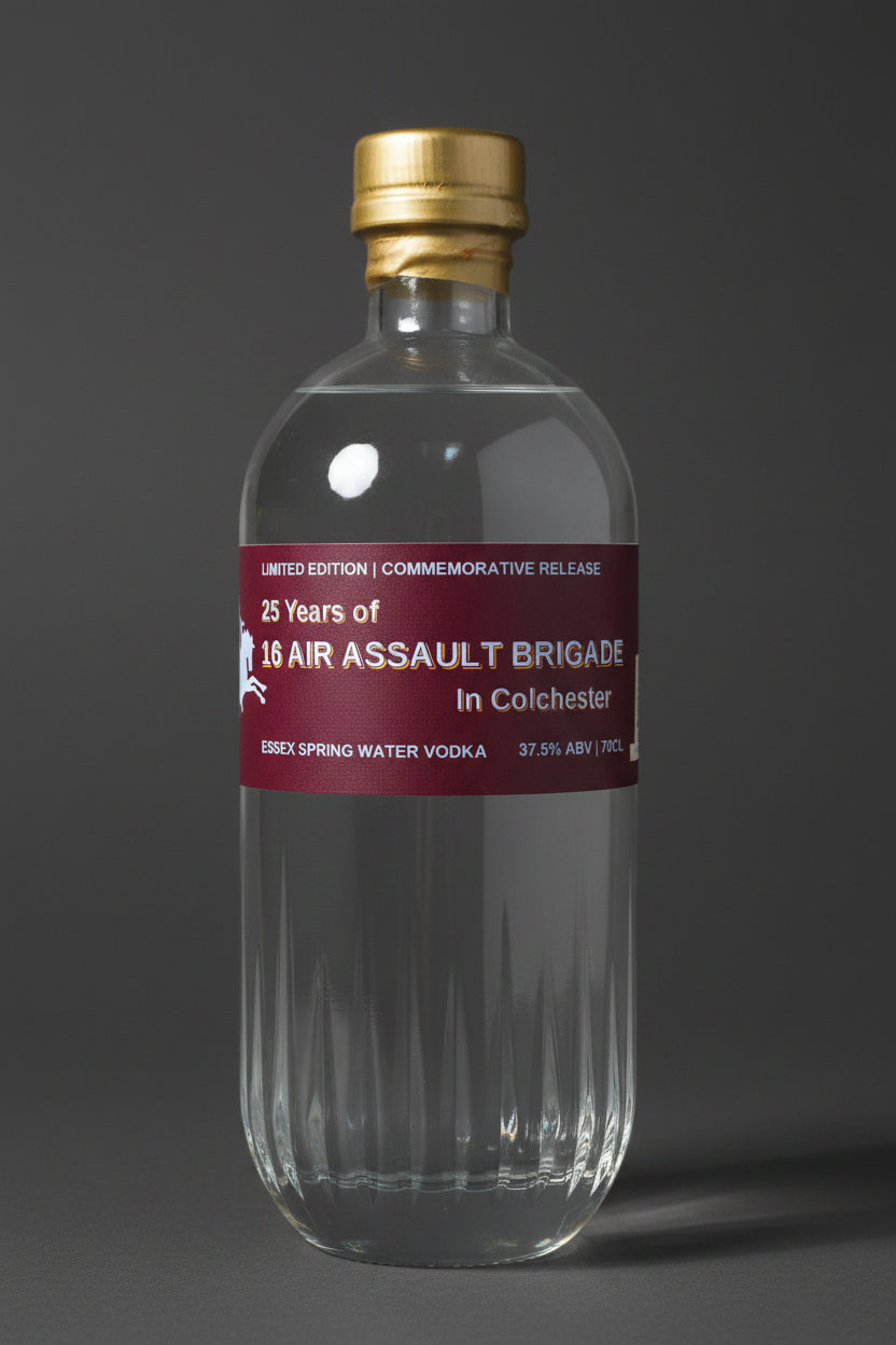 A clear glass bottle of Essex Spring Water Vodka with a gold cap and a dark red label reading '25 Years of 10th Air Assault Brigade in Colchester'.